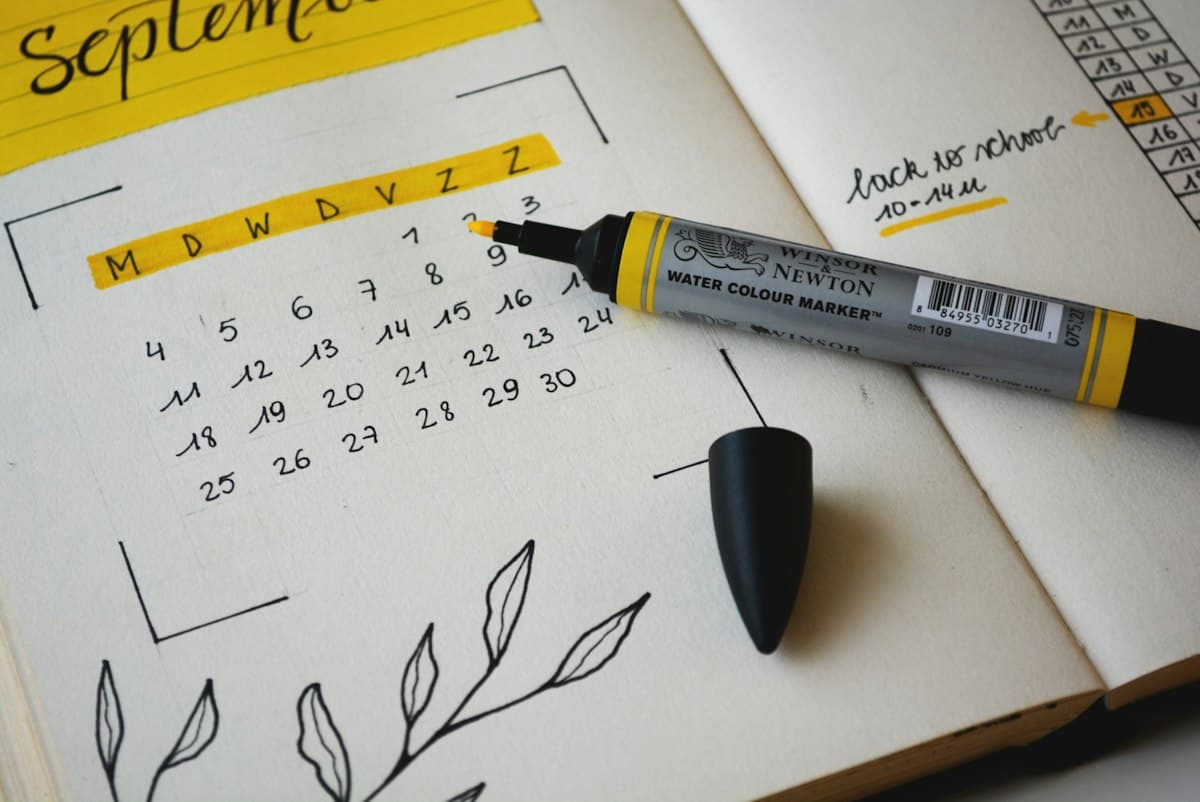 Arbeitsplatz mit Kalender, Notizbuch und Smartphone zur reibungslosen Terminabstimmung